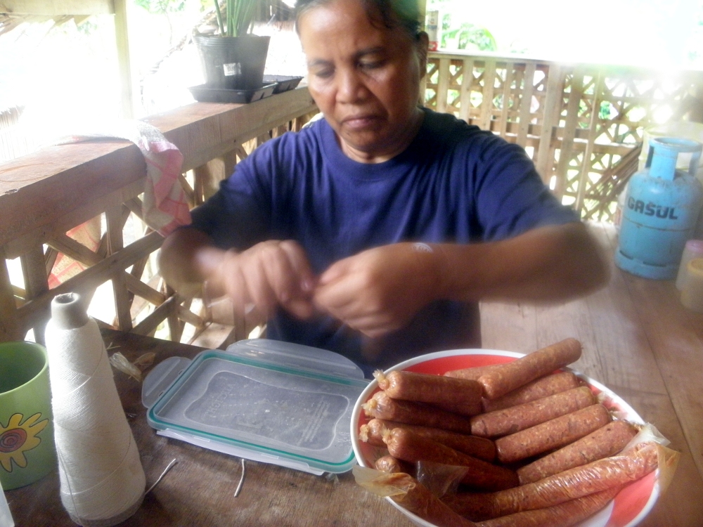 Here's Penny linking sausages. We use commercial sausage casings because we don't have enough of our own casings. Often, pork intestines are cooked in the popular pork blood stew called 